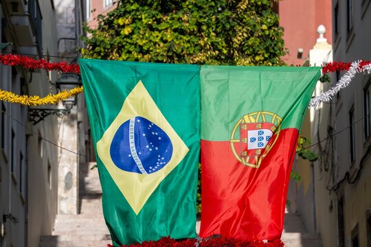 View of the flags of Brazil and Portugal hanging in a narrow street in Lisboa, Lisboa, Portugal.