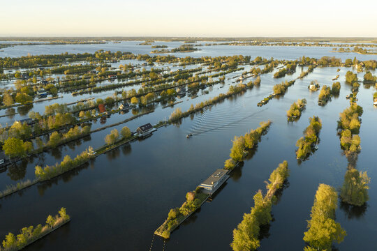 Aerial view of Scheendijk in the Loosdrechtse Plassen, featuring narrow strips of land with houses and trees surrounded by calm water, Breukelen, Utrecht, Netherlands.