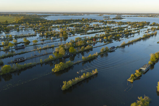 Aerial view of Scheendijk, featuring narrow strips of land with small houses and lush trees surrounded by the calm waters of the Loosdrecht lakes in Breukelen, Utrecht, Netherlands.