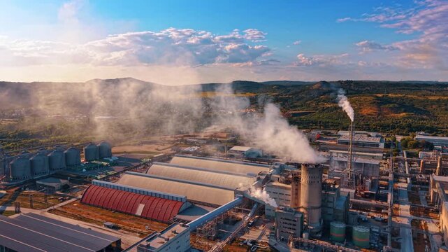Pipes of the industrial plant produce muck smoke. Flight over the territory of the industrial factory in the countryside.