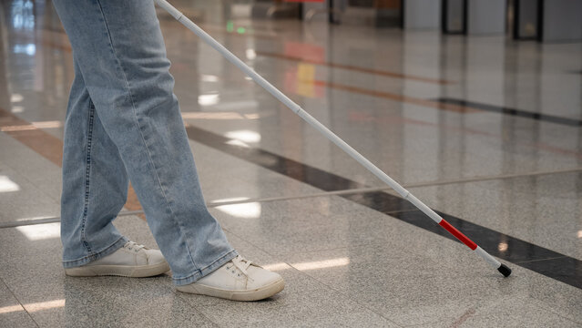 A blind woman walks using a walking stick.