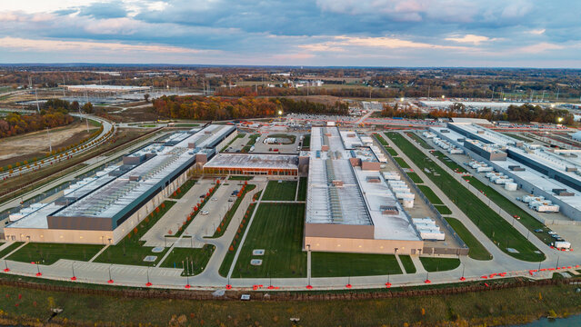 Aerial view of a large data center facility with expansive rooftops, cooling units, and parking areas surrounded by green lawns and autumn trees in New Albany, Ohio, United States.