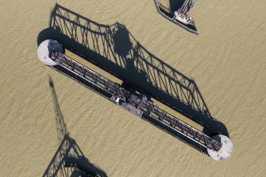 Aerial view of a metal bridge structure spanning over the water with long shadows cast on the surface in Toledo, Ohio, United States.