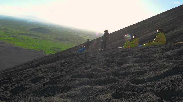 Tourists sandboarding on Cerro Negro, Leon, Nicaragua. Group of adventurers sandboarding down a volcano at sunset