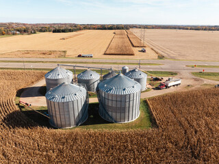 Elevated drone perspective of silver grain silos complex surrounded by ripe corn fields and semi truck © Nick