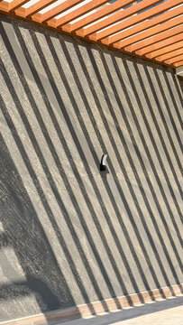 Abstract architectural shadows from a wooden pergola creating striking diagonal lines on a textured modern wall. Minimal geometric background with sunlight, pattern and copy space for contemporary 