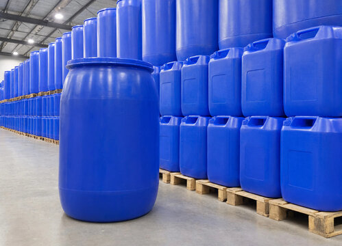 Rows of blue plastic chemical drums neatly stacked on pallets in industrial logistics warehouse