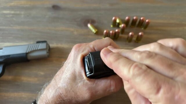 Closeup of loading a semi-automatic handgun's magazine with .45 ACP cartridges using an auto loader.