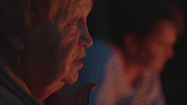 Elderly woman sits in front of the bonfire burning in the wild area