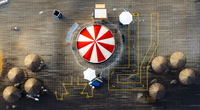 Aerial view of Tel Aviv Port featuring a red and white striped carousel on a wooden deck with umbrellas and yellow markings in Tel Aviv-Yafo, Tel Aviv District, Israel.