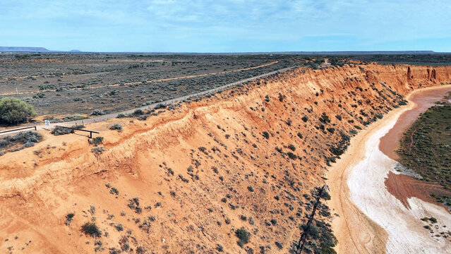 Aerial view of the Matthew Flinders Red Cliff Lookout featuring dramatic red earth cliffs, desert vegetation, and a road along the ridge in Port Augusta West, South Australia, Australia.