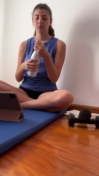 Young woman resting after an online home workout and using a tablet for an online class