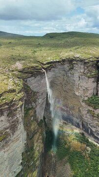 Aerial view of the dramatic Cachoeira da Fumaca waterfall cascading down steep rocky canyon cliffs in the lush landscape of Palmeiras, Bahia, Brazil.