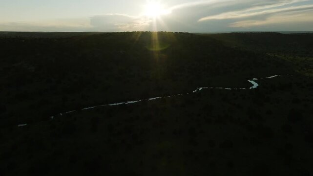 Wide aerial view of a winding river at sunset in a dark valley, drone shot over wilderness landscape