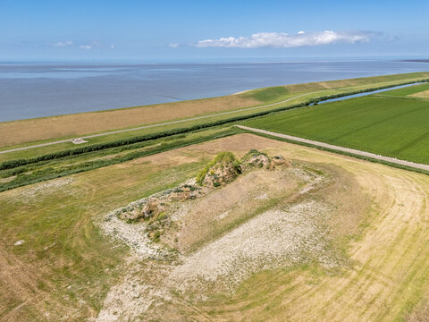 Aerial view of the historic terp Dijk van een wijf surrounded by agricultural fields and the Wadden Sea dike in Oosterbierum, Friesland, Netherlands.
