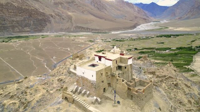 Aerial view of ancient monastery with stone walls and white-washed architecture set against the arid mountain landscape of the Zanskar valley in Zanskar, Ladakh, India.