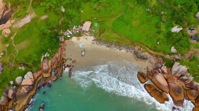 Aerial view of Praia do Gravata with rocky coastline, sandy beach, and turquoise waves in Florianopolis, Santa Catarina, Brazil.
