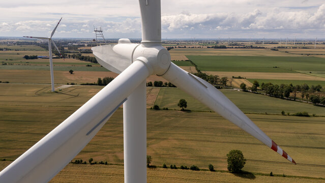 Aerial view of wind turbines standing in vast agricultural fields under a cloudy sky in Nowy Dwor Gdanski, Pomeranian Voivodeship, Poland.