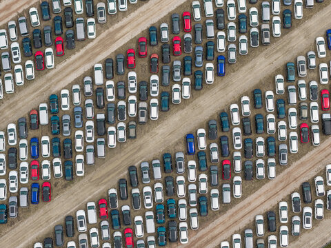 Poland - 11 July 2026: Aerial view of a large car storage lot featuring rows of parked vehicles arranged in diagonal lines on a dirt surface.