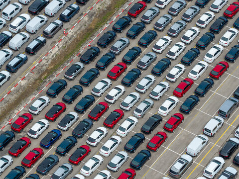 Poland - 11 July 2026: Aerial view of rows of new cars parked in a large storage lot, showcasing a variety of colors and models arranged in neat lines on asphalt.