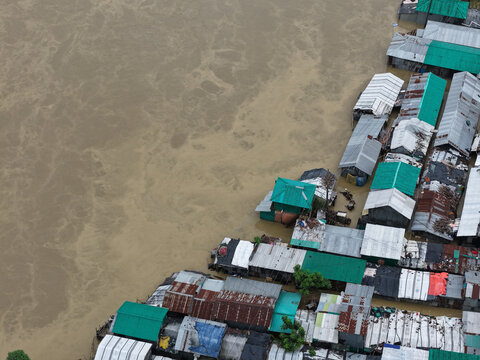 Satkania, Chittagong Division, Bangladesh - 11 July 2026: Aerial view of flooded houses with tin roofs partially submerged in muddy floodwater.