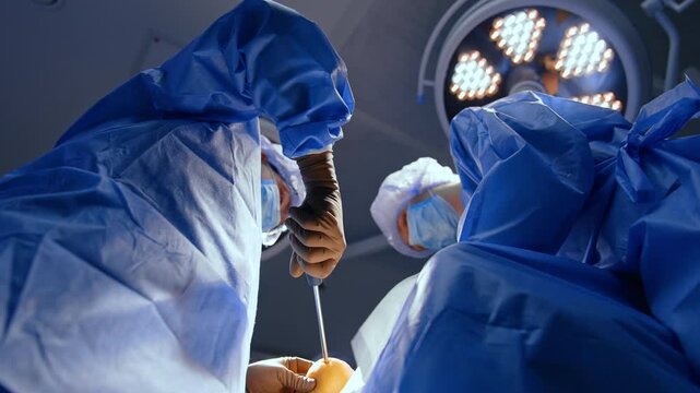 Male doctor uses a surgical screw-driver at the heel of the patient. Modern surgery on foot trauma. Low angle view.