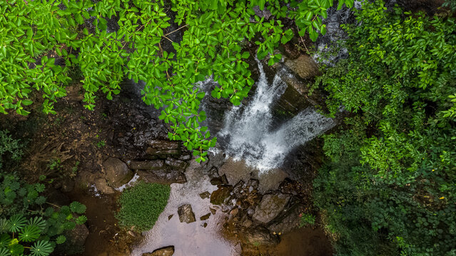 Aerial view of Oboadaka Falls cascading over rocky cliffs into a pool surrounded by dense tropical forest in Aburi, Eastern Region, Ghana.