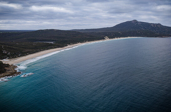 Aerial view of Bettys Beach with turquoise water, sandy coastline, and rolling hills under a cloudy sky in Albany, WA, Australia.