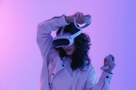 Young asian woman engaging in virtual reality experience with headset in neon lighting