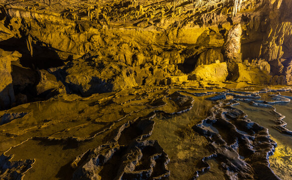 View of Nguom Ngao Cave with intricate limestone formations, stalactites, and reflective water pools in Dam Thuy, Cao Bang, Vietnam.
