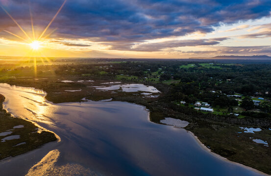 Aerial view of the Lower King river estuary at sunset with golden light reflecting on the water, surrounded by lush greenery and rural landscape in Lower King, Western Australia, Australia.