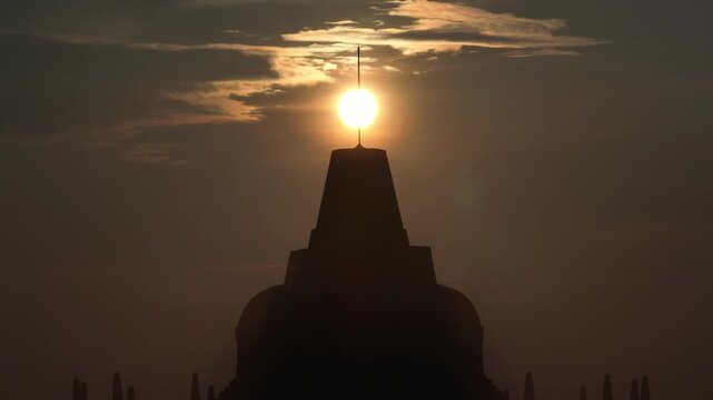 Aerial view of Borobudur Temple silhouetted against a golden sunset sky in Kecamatan Borobudur, Jawa Tengah, Indonesia.