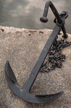 Weathered boat anchor resting on a concrete pier by the water