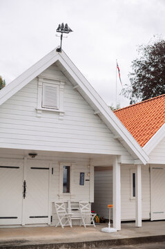 Traditional white boathouse with ship weather vane and Norwegian flag