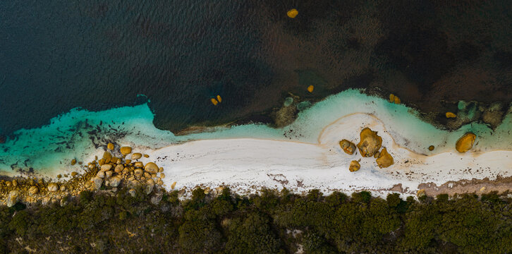 Aerial view of Two Peoples Bay featuring a white sand beach, turquoise water, and large granite boulders surrounded by lush coastal vegetation in Nanarup, Western Australia, Australia.