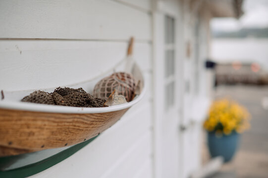 Decorative wooden boat filled with fishing nets and driftwood on a white wall