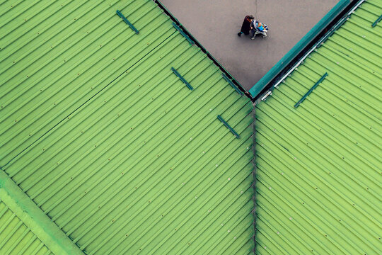 Aerial view of a person walking on a path next to a bright green corrugated metal roof in Belgrade, City of Belgrade, Serbia.