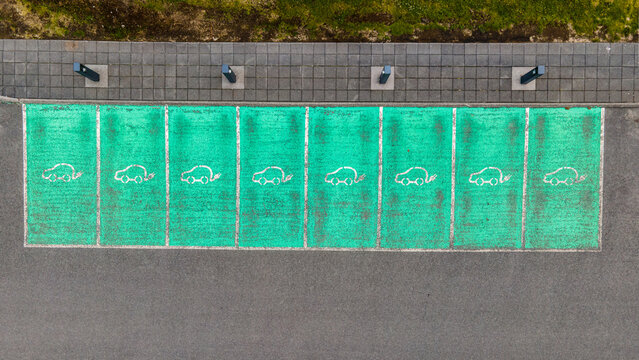 Aerial view of an electric vehicle charging station with green painted parking spaces marked by white car icons in Reykjavik, Reykjavikurborg, Iceland.