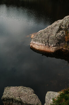 Rocky shoreline with dark water and subtle ripples in Norway
