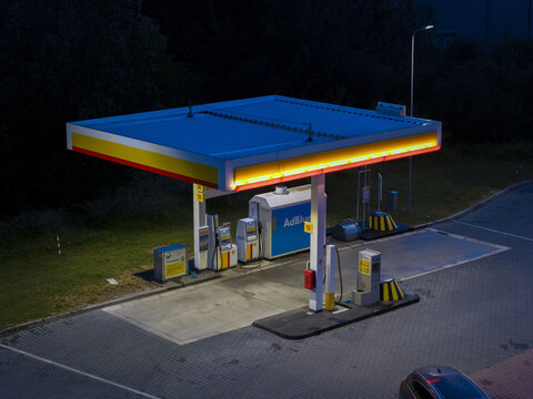 Krakow, Poland - 05 July 2026: Aerial view of a Shell station at night, featuring illuminated fuel pumps, a canopy with yellow and red branding, and a paved forecourt.