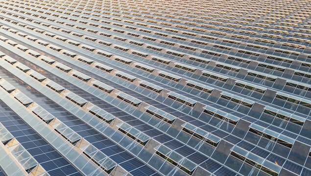 Aerial view of a commercial greenhouse roof covered with photovoltaic solar panels, illustrating sustainable horticulture and clean energy production in Saulce-sur-Rhone, Auvergne-Rhone-Alpes, France.