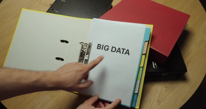 Opening a ring binder containing documents labeled "BIG DATA". Ideal for data analytics, data management, business intelligence, digital transformation, and information technology concepts.