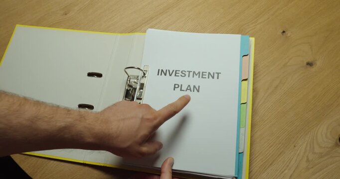 Opening a ring binder to reveal an investment plan document. Ideal for financial planning, wealth management, investing, business strategy, and personal finance concepts.