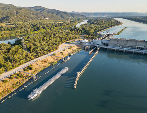 Saulce-sur-Rhone, France - 12 July 2026: Aerial view of a cargo barge approaching the navigation lock at the Rhone River hydroelectric power station.