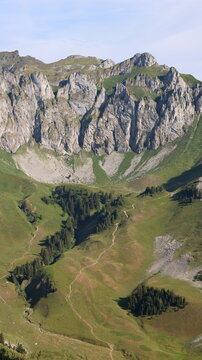 View of Cornettes de Bise mountain peak with rocky cliffs, lush green alpine meadows, and winding hiking trails in La Chapelle-d'Abondance, Auvergne-Rhone-Alpes, France.
