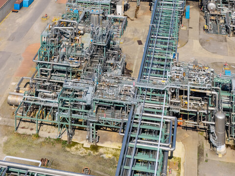 Aerial view of an industrial chemical refinery complex featuring intricate networks of steel pipes, processing units, and storage tanks in the United Kingdom.