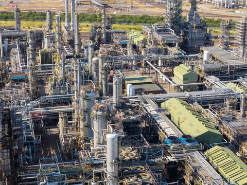 Aerial view of an industrial oil refinery complex featuring intricate networks of pipes, storage tanks, cooling towers, and metallic structures in the United Kingdom.
