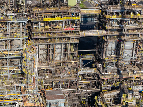 Aerial view of an industrial refinery complex with complex networks of pipes, metal structures, and towers in the United Kingdom.