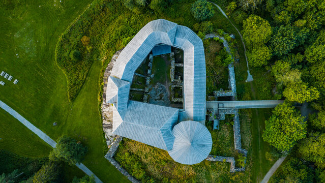 Aerial view of Raseborg Castle ruins with grey shingle roofs, stone walls, and surrounding lush green forest in Raasepori, Uusimaa, Finland.