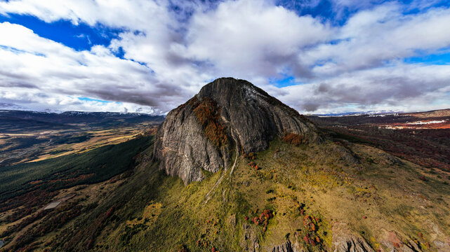 Aerial view of the rugged Cerro Mackay mountain with autumn foliage and dramatic clouds over the vast landscape in Coyhaique, Aysen, Chile.